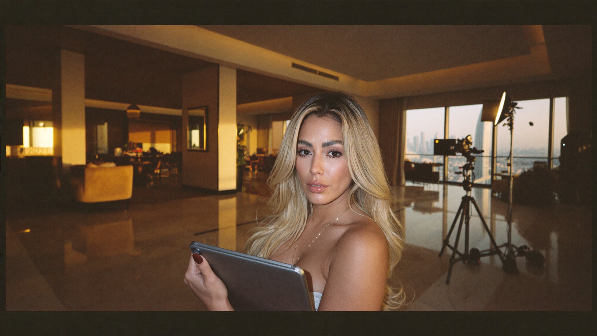 Creative director reviewing a tablet on a brand content shoot in a luxury Dubai interior with camera equipment visible in the background